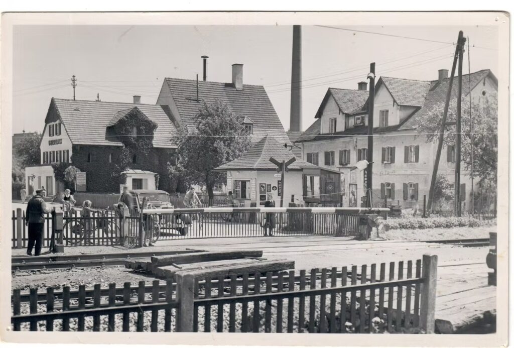 Ansichtskarte von Bäumenheim: Bahnübergang mit Kiosk, Bäckerei Oberfrank, Mädchenheim, Plakatwand